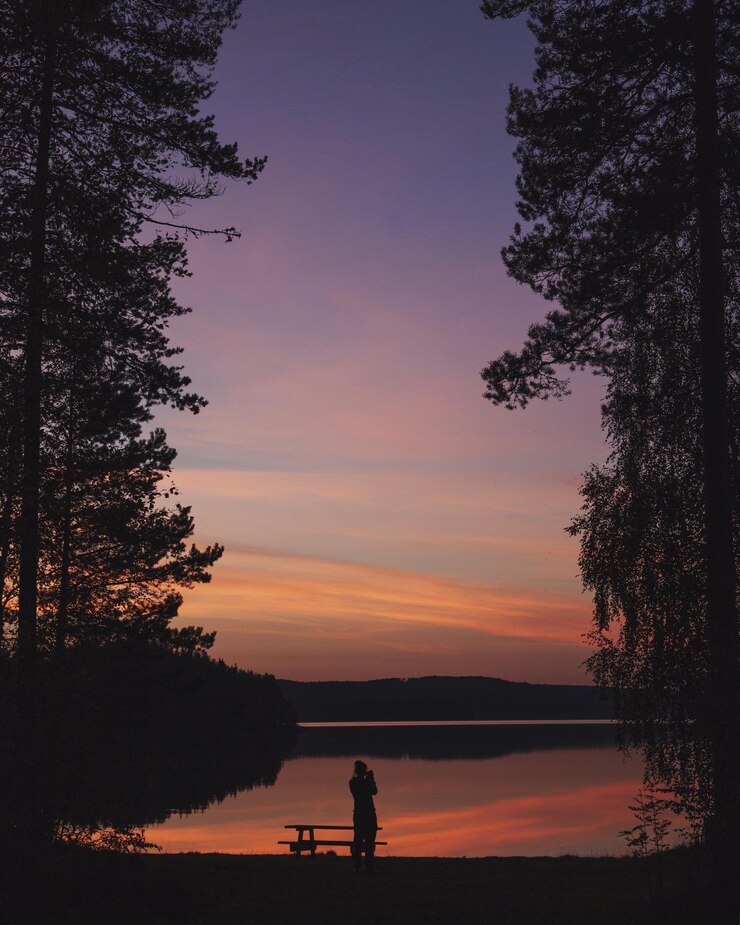 Foto silhueta de uma pessoa na margem do lago ao anoitecer