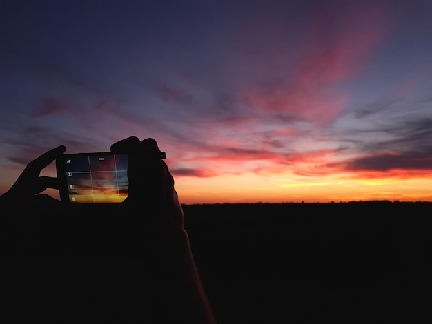 Foto silhueta de uma pessoa no campo contra o céu durante o pôr do sol