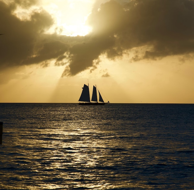 Silhueta de veleiro navegando no mar contra o céu durante o pôr do sol