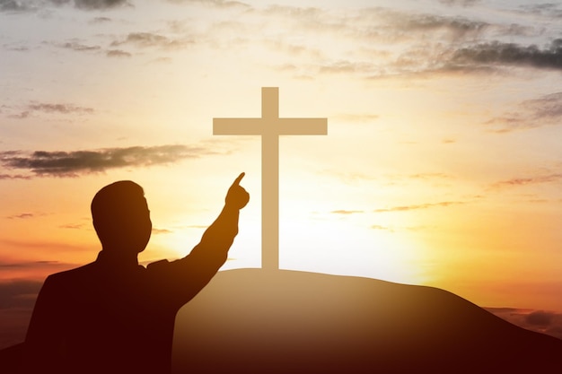 Silhueta do empresário apontando a cruz cristã na colina