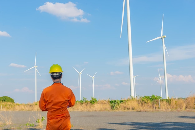 Silhueta do engenheiro homem trabalhando e segurando o relatório na estação geradora de energia da fazenda de turbinas eólicas na montanhaTailândia