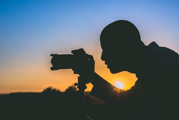 Silhueta do fotógrafo com tripé ao pôr do sol