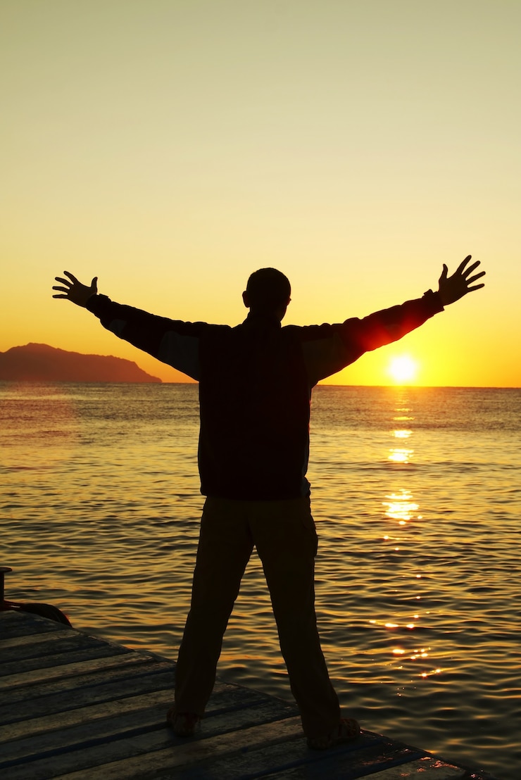 Silhueta do homem feliz ao pôr do sol