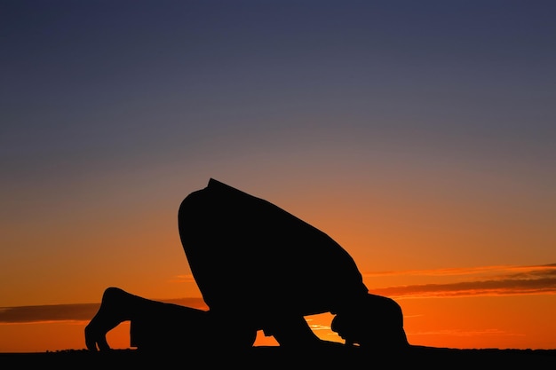 Silhueta do homem muçulmano rezando ao pôr do sol Mês sagrado do Ramadã
