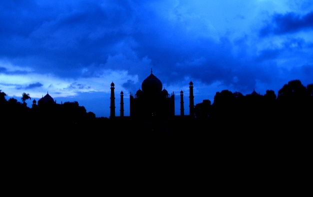 Foto silhueta do taj mahal contra o céu dramático durante o pôr do sol