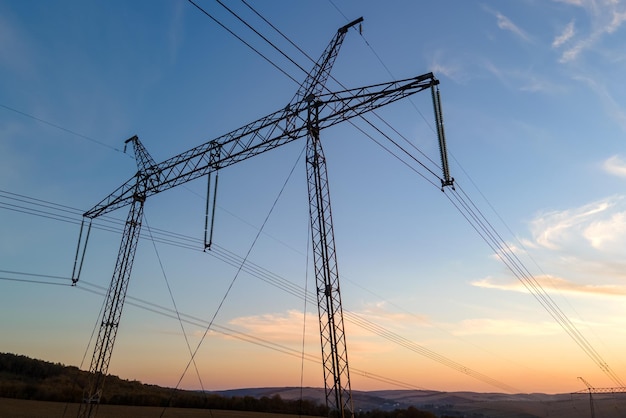 Silhueta escura da torre de alta tensão com linhas de energia elétrica ao nascer do sol Transmissão do conceito de energia elétrica