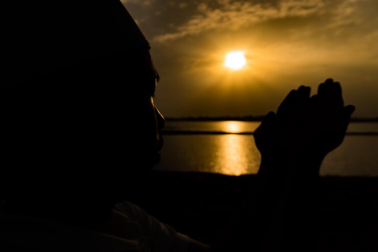 Silhueta jovem muçulmano asiático rezando no pôr do sol conceito do festival do Ramadã