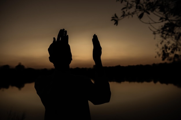 Silhueta jovem muçulmano asiático rezando no pôr do sol conceito do festival do ramadã