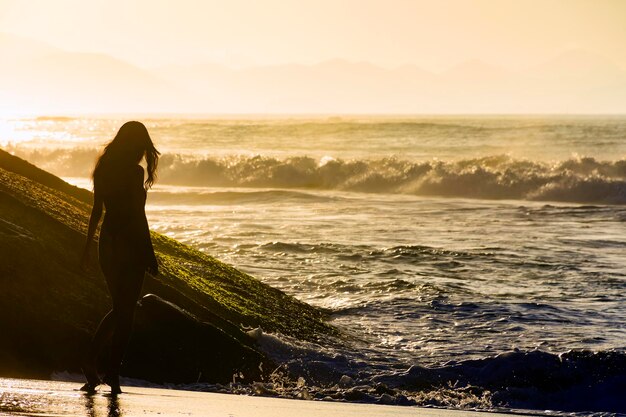 Foto silhueta de una joven al amanecer de verano en la playa de ipanema en río de janeiro