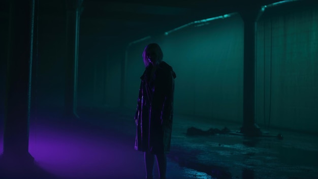 Foto silhueta misteriosa de una mujer en un pasillo oscuro con una luz de neón brillante