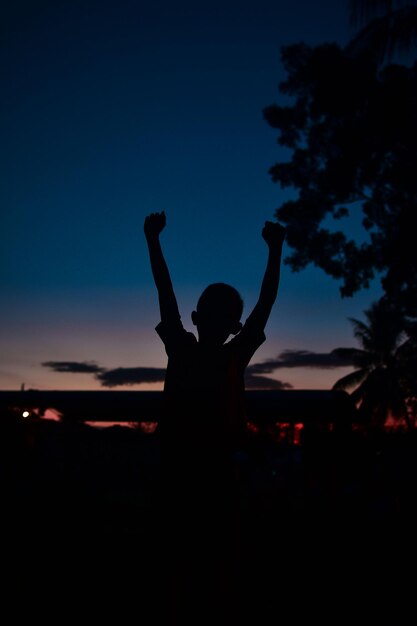 Foto silhueta de mujer con los brazos levantados contra el cielo al atardecer