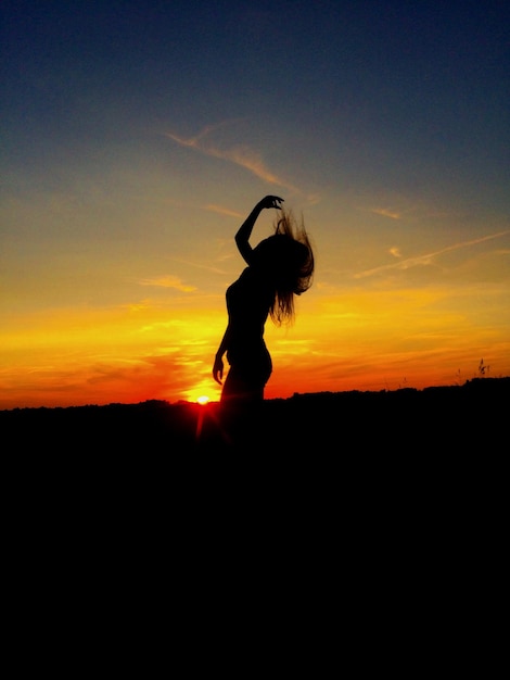 Foto silhueta de mujer con el cabello desordenado contra el cielo durante la puesta de sol