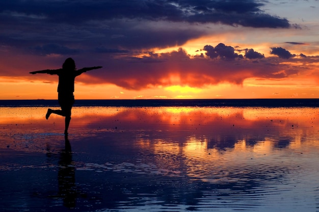 Silhueta de una mujer en un lago salado durante la puesta de sol