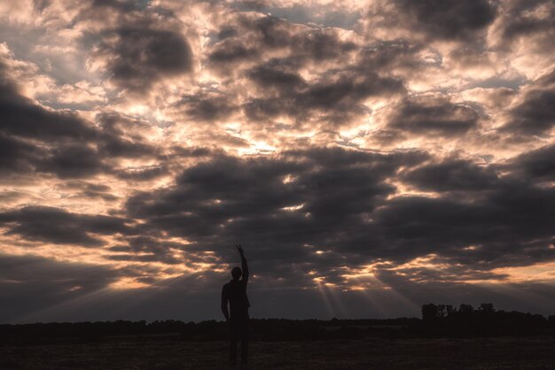 Foto silhueta de una mujer de pie en tierra contra el cielo durante la puesta de sol