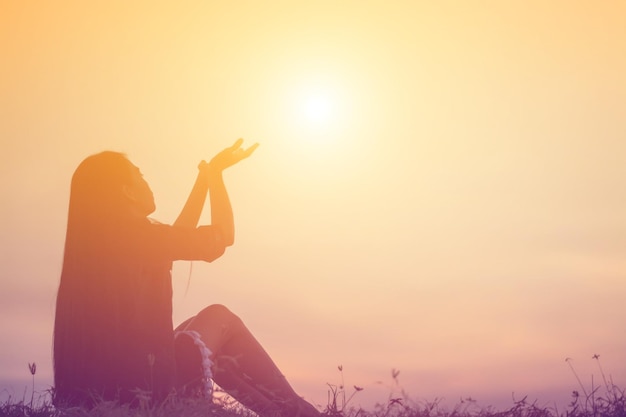 Silhueta de una mujer sentada contra el cielo durante la puesta de sol