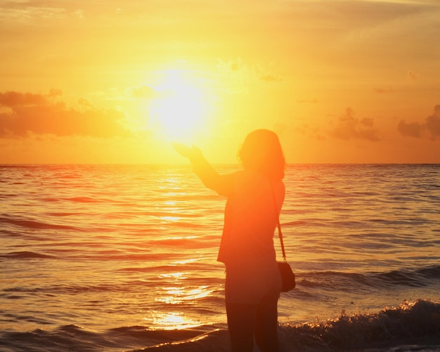 Foto silhueta de mujer sosteniendo el sol en la playa