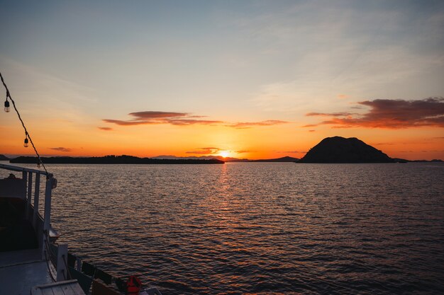 Silhueta negra de colinas com reflexo do sol no mar em labuan bajo