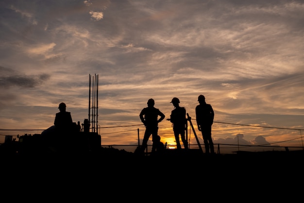 silhueta o grupo de trabalhadores que trabalham em um canteiro de obras.