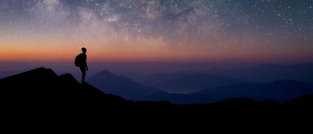 Silhueta panorâmica de jovem viajante com mochila em pé e assistiu a estrela e a via láctea sozinho no topo da montanha Ele gostava de viajar e foi bem sucedido quando chegou ao cume