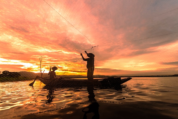 Silhueta pescador pesca usando net no barco de manhã na tailândia, natureza e conceito de cultura