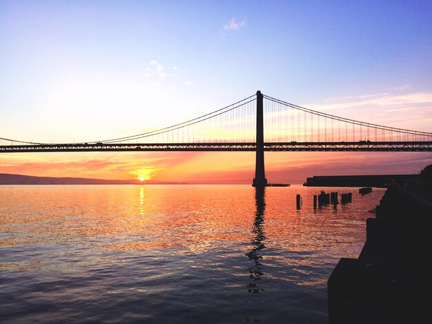 Foto silhueta del puente de la bahía contra el cielo durante la puesta de sol