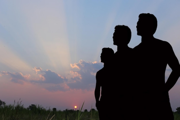 Silhuetas de amigos de pie contra el cielo durante la puesta de sol