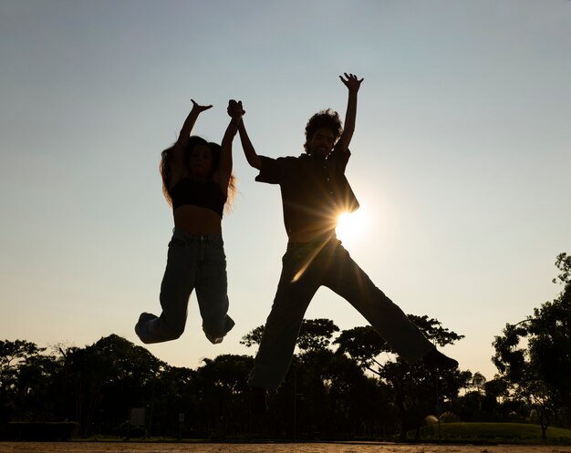 Foto silhuetas de amigos de tiro completo pulando ao pôr do sol