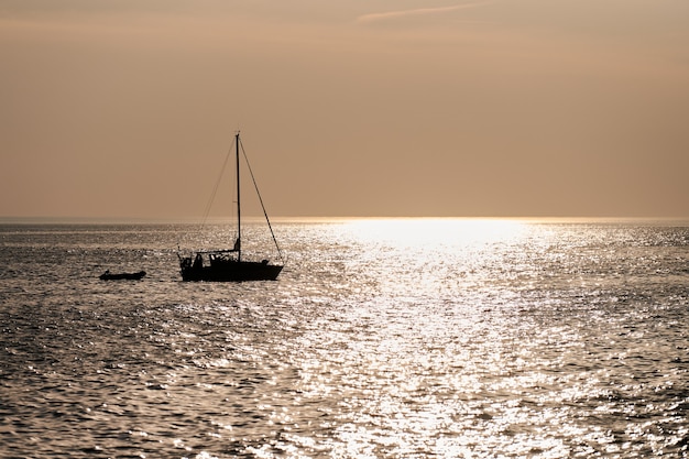 Silhuetas de barcos à vela no fundo do belo pôr do sol laranja, a luz do sol refletindo na água do mar calma. paisagem marítima horizontal com dois veleiros de pesca conectados, paisagem do mar báltico