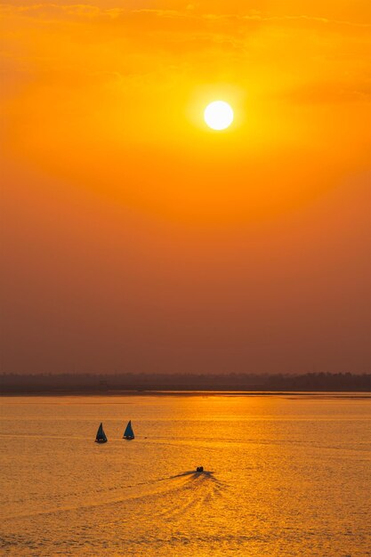 Silhuetas de barcos de iate no lago no pôr do sol Índia