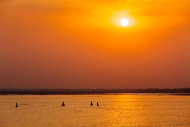 Silhuetas de barcos de iate no lago no pôr do sol