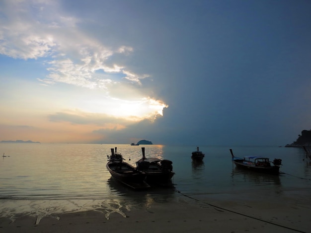 Silhuetas de barcos no mar contra o céu durante o pôr do sol