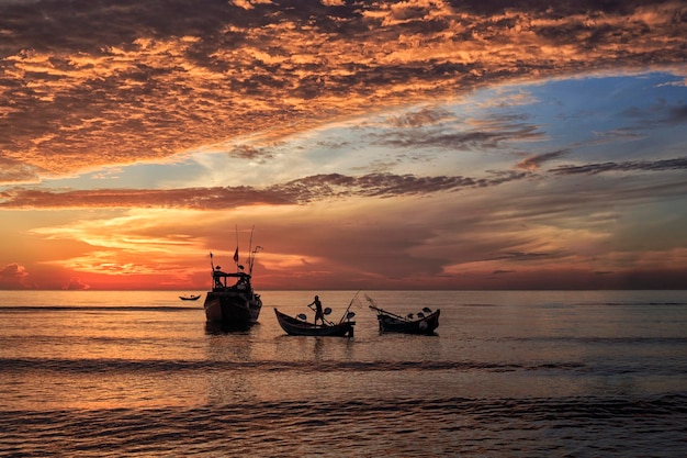 Silhuetas de barcos no mar contra o céu durante o pôr do sol
