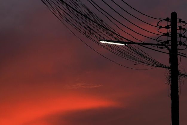Silhuetas de fios de postes elétricos e luzes no fundo do céu crepuscular