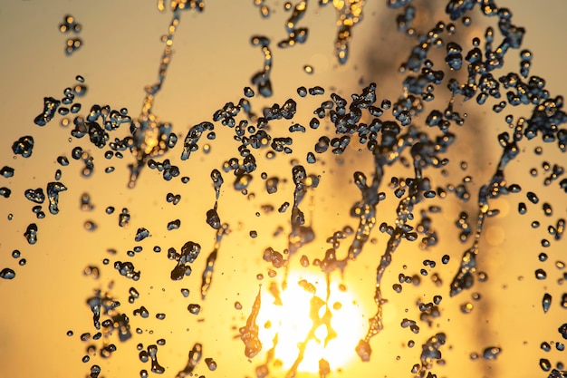 Silhuetas de gotas caindo da fonte de água no sol poente