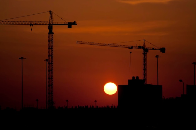 Foto silhuetas de guindastes contra o céu ao pôr-do-sol