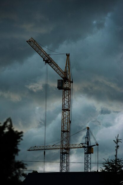 Silhuetas de guindastes de construção contra o fundo de um lindo céu tempestuoso
