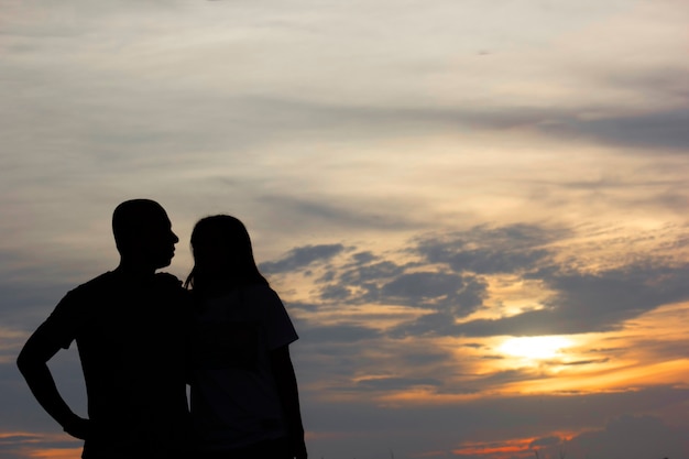 Silhuetas de homens e mulheres jovens, observando o sol durante o crepúsculo.