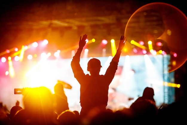 Silhuetas de pessoas com as mãos levantadas em um concerto. luz de palco.