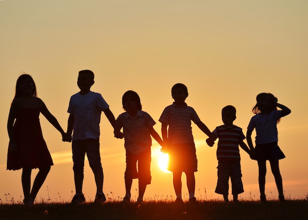 Silhuetas de pessoas felizes na natureza ao horário do por do sol