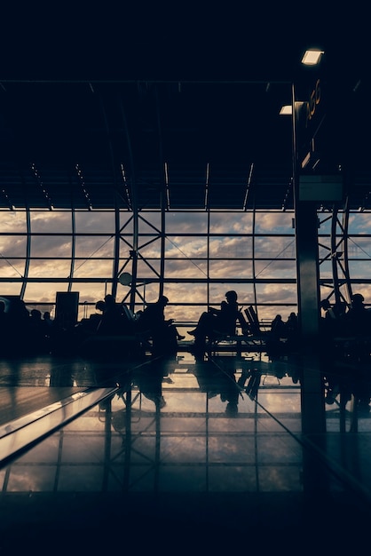 Foto silhuetas desfocadas de executivos que viajam no aeroporto; esperando nos portões de embarque do avião.