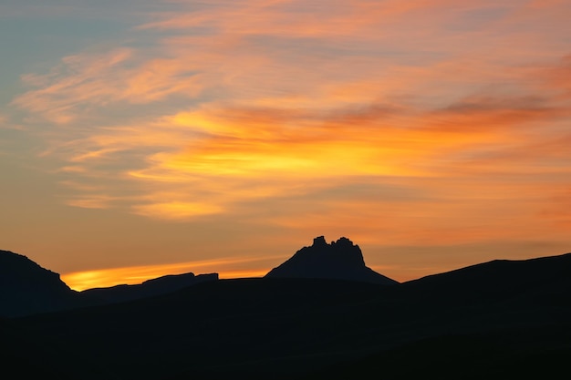 Silhuetas escuras de montanhas contra um céu brilhante de pôr do sol laranja Pôr do sol vermelho sobre montanhas majestosas Pôr do sol em tons de magenta Paisagem roxa atmosférica com um vale de montanha nevada de alta altitude