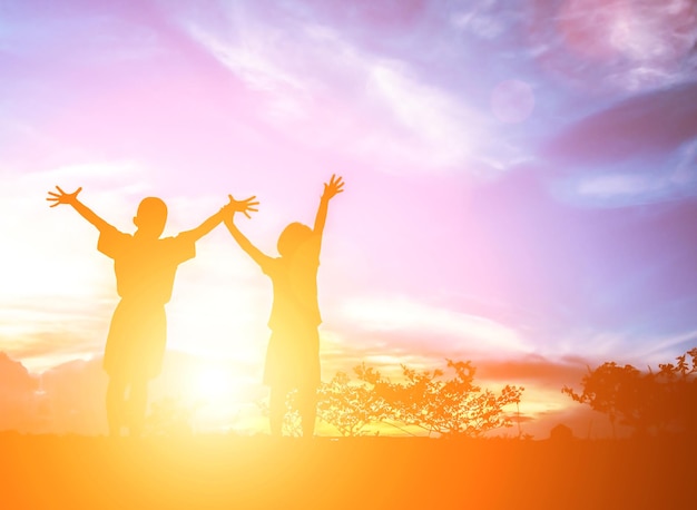 Silhuetas felizes de pessoas contra o céu durante o pôr-do-sol