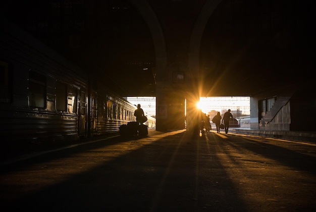 Silhuettes de personas caminando hacia el atardecer del tren