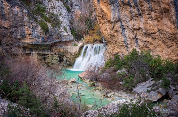 Silky Water Wasserfall mit fallendem Baumstamm und Blick auf die Gehwege von Alquezar Huesca Spanien