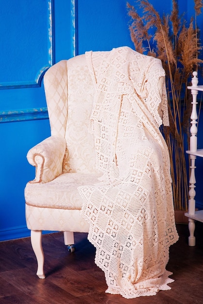 Silla beige sobre un fondo azul Una silla con una manta encima