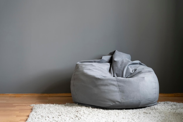 Una silla de bolsa gris o un sillón de frijoles en casa en la sala de estar