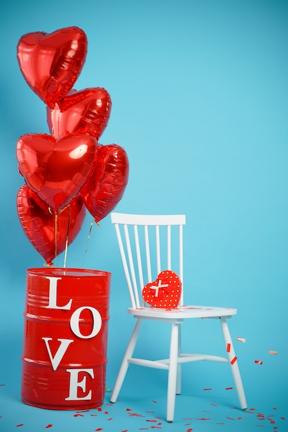 Foto silla con caja en forma de corazón y globos rojos