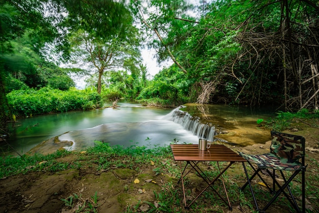 Silla de camping con mesa frente a la cascada de vacaciones