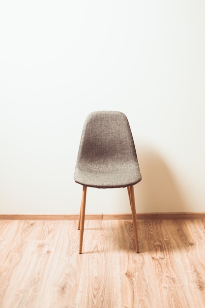 La silla está cerca de la pared en la habitación vacía.