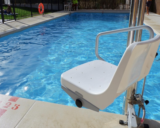 Silla hidráulica para personas con discapacidad en la piscina accesible en patio interior en Madrid España